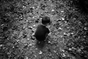 grayscale photo of child sitting on ground